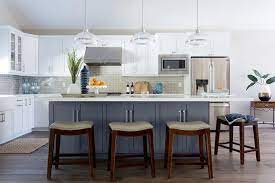 The dark granite countertop complements the woodwork and the dark glass in the stainless steel appliances. White Cabinets With Dark Gray Island Transitional Kitchen