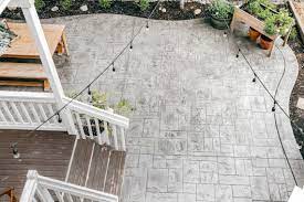 Wooden planks were used to stamp the concrete to create the parquet floor appearance. What To Expect When Installing A Curved Stamped Concrete Patio A Light Grey Ashlar Slate Patio Design Rain And Pine