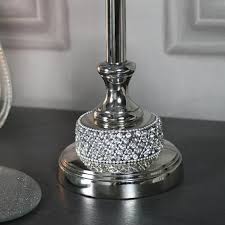 The glass base rendered in a white glass with gold glitter finish brings a hint of color to any space. Silver Nickel Diamante Table Lamp