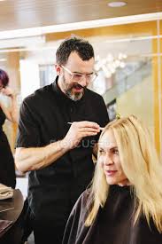 The steps involved are similar to that of hair dyeing. Mature Male Hairstylist Working On Client Hair And Applying Hair Dye In Salon Coloring Hairstyling Stock Photo 192703994