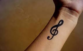 The musical tattoo idea in grey shades depicting piano keyboard and the guitar necks and a musician hands playing on it. Music Tattoos Ideas New Tattoo Designs With Meaning