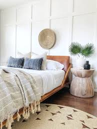 A pretty modern coastal bedroom with beadboard walls, blue bedding, a nautical artwork, wooden furniture and a jute rug. Coastal Bedroom Ideas The Heart And Haven