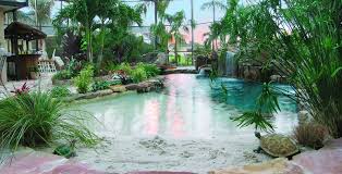 Natural Lagoon Pool With Sand Bottom Entryway Into Lagoon Pool With A Swim Up Water Feature And Wooden Brid Backyard Pool Landscaping Backyard Pool Lagoon Pool