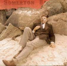 The dead man reclined against a beach wall that morning in a suit and tie, with an unlit cigarette resting on his collar, as if merely dozing on the pristine sand. Somerton Man The Print