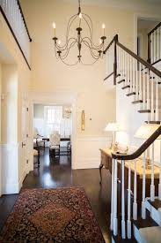Rustic chandelier lighting fixtures look stunning in a country cottage or traditional home. Elegant Entryway With Lofted Ceilings Open Stairway Dark Wood Floors And A Rustic Chandelier Rustic Chandelier Chandelier Decor Elegant Entryway