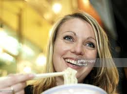 Woman Eating Noodles Smiling Low Angle View High-Res Stock Photo