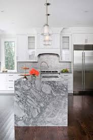 White Kitchen Cabinets Paired With Marble Countertops And Stainless Steel Linear Tile Backsplash Jo Marble Kitchen Island Kitchen Marble Grey Marble Kitchen