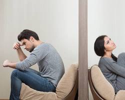 Imagem de pastor and his wife sitting on a couch, looking sad and distant
