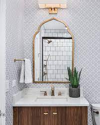 A Gold Sconce Lights A Gold Arch Vanity Mirror Hung From A Wall Covered In White And Gray Quatrefoil Wallpa Bathroom Mirror Gold Wallpaper Bathroom Gold Sconce