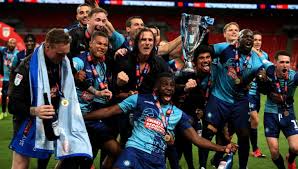 The chairboys' 13/14 home jersey uses wycombe's trational quartiles in the club's light blue and black on its front torso. The Biggest Little Club In The World Why Wycombe Wanderers Promotion To The Efl Championship Is A Huge Deal Urban Pitch