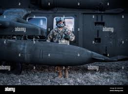 A U.S. Soldier assigned to Charlie Company, 3-227th Aviation Regiment,  Combat Aviation Brigade, 1st Cavalry Division poses beside a UH60M  Blackhawk during an aerial reconnaissance training event at Military  Training Area Lest,