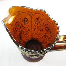 At its zenith, carnival glass — a type of pressed glass with an unmistakable iridescent glaze — offered consumers a sophisticated aesthetic at an accessible price point. Antique Imperial Amber Fieldflower Carnival Glass Water Pitcher Carnival Glass