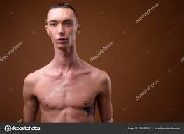 年轻英俊的雌雄同体男子赤裸的对棕色背景——图库图片© amazingmikael 225436246