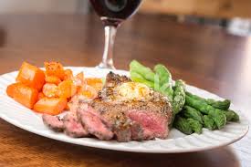 The meal is presented on a square white plate on a light wooden table. Big Rib Eye Steak Stock Photos Freeimages Com