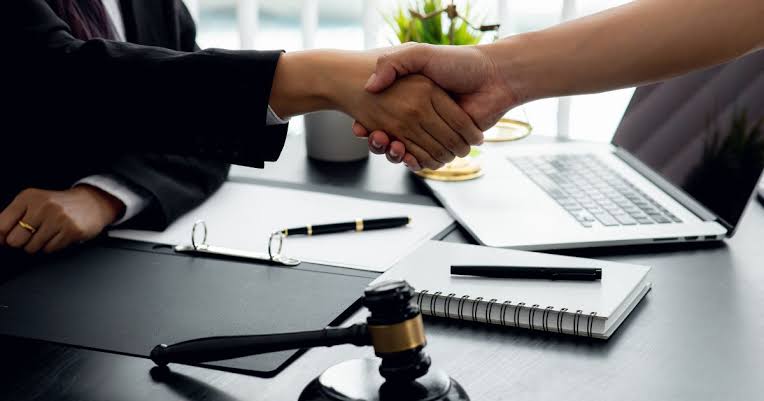 Attorney shaking hands with client in Texas law office