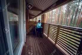 Proyecto de casa de dos pisos 1 piso solido 2 piso de madera 2 piso con terraza casa de 150 mts aprox es casa para campo melipilla región. Nina En Un Sueter Azul Sentado En Una Silla De Madera Y Beber Te De Una Taza Blanca En La Terraza Del Segundo Piso Balcon En La Casa En El Bosque De
