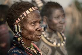 An old Mundari woman covered in red ochre and oil at a child naming  ceremony at one of the cattle camps in South Sudan. Her face was clearly a  reflection of a