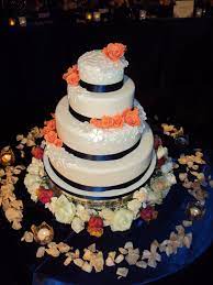 White 4 Tier Wedding Cake With Royal Blue Trimming And Peach Flower Decoration Navy Blue Wedding Cakes Wedding Cake Navy Coral Wedding Cakes