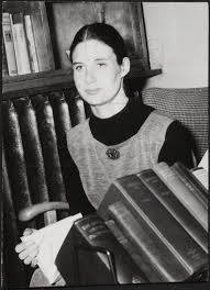 Photograph of Jay Macpherson sitting holding a book with books in front of  her]