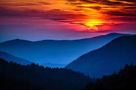 Silhouette of hills under orange and yellow sky during sunset, silhouette mountain during golden hour, grayscale photo of trees near body of water. 7 Of The Best Places To See A Sunset In The Smoky Mountains