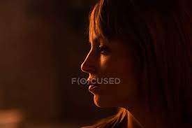 Emotionless Young Woman Face With Bangs Standing In Soft Gold Light Of Sunset And Looking Away Natural Shadows Stock Photo 214402354