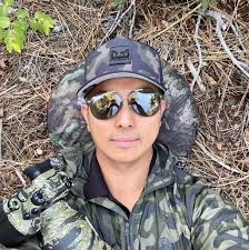 Black bear in a tree with fall leaves. Awcc