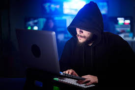 hacker using laptop with hoodie, smartphone nearby, cyber attack concept
