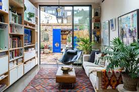 A colorful eclectic living room with a green statement wall with artworks, a boho rug, a mustard sofa and wicker touches. 16 Ravishing Eclectic Living Room Interiors You Will Adore