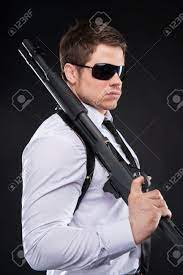 Guardaespaldas. Vista Lateral De La Joven Confía En Camisa Y Corbata Con El  Arma Y Mirando A Otro Lado Mientras Está De Pie Contra El Fondo Negro  Fotos, Retratos, Imágenes Y Fotografía
