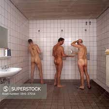 Rear view of three naked men taking shower - SuperStock
