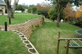 Retaining walls increase the usable space in a yard by flattening the base of the slope. A Steep Garden Transformed With Retaining Wall Blocks Sloped Garden Steep Gardens Garden Retaining Wall