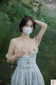 tw: @NanaModelte Jrants.com  An Asian woman wearing a floral dress and a  face mask poses outdoors near water. twi: @NanaModel  An Asian woman sits  on a bench outdoors, wearing a