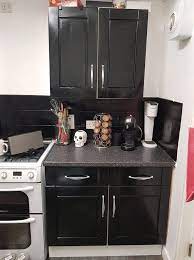 The organic texture of the wooden particles is supplemented by the shining gloss coming from the black paint. Woman Spends 43 Transforming Her Kitchen Using Black Cupboard Paint And Enamel Spray