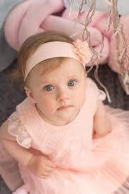 Una niña con un vestido rosa y un lazo rosa en la cabeza