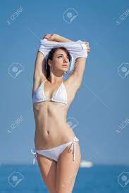 ビーチで脱いでいる白い水着で海の魅力的なブルネットの女の子の写真素材・画像素材 Image 19337329