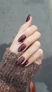 Submitted 2 years ago by clockticktocks. Dark Burgundy Red Nail Polish On Acrylic Nail Shapes Worn By A Pale Hand Dressed In A Brown Chunky Knitted Sleeve