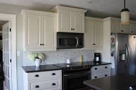 The metallic refrigerator and hardware infuse the masculine character into the zone. White Kitchen Cabinets Black Countertops Backsplash Decorkeun