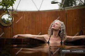 Mature woman relaxing in hot tub at eco retreat — relaxation, wood - Stock  Photo | #164903572