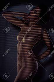 Sensual Retrato De Una Hermosa Mujer Desnuda En Una Pose Elegante Con Su  Armado Levantó El Cuerpo Y Destacan Por Las Sombras Rayadas Fotos,  retratos, imágenes y fotografía de archivo libres de