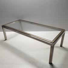 The design is contemporary, and the translucent top shows off the ironwork to best advantage. Vintage Chrome Brass Coffee Table With A Glass Top 106028