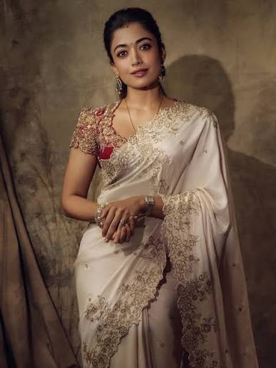 Rashmika Mandanna (@rashmika_mandanna) radiates understated elegance in an  ivory embroidered saree paired with a richly embellished blouse that adds a  regal contrast to the look. The delicate detailing along the drape, combined