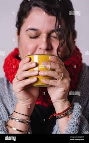 Vertical image of a woman drinking tea from a yellow cup. She warms up  having something hot. Winter concept Stock Photo