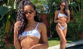 Laura Harrier flashes underboob in a tiny white bikini for sunbathing  session 
