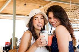 Zwei junge Frauen trinken Cocktails in Strandbar, lizenzfreies Stockfoto