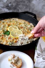 A Close Up View Of A Cast Iron Skillet Filled With Shrimp Scampi Dip The Golden Top Is Garnished With 2 Creamy Shrimp Scampi Shrimp Scampi Dip Appetizer Bites