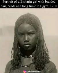 Portrait of a bisharin girl with braided hair, beads and long tunic in  Egypt, 1910.