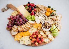 Top view of tray with pieces of cheese, dried olives, pistachios, slices of pear, grapes and knife on grey background. How To Make A Fruit And Cheese Platter I Heart Naptime