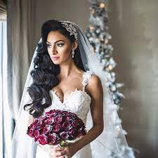 The vintage updo combines rolled bangs, a small victory roll, and a low ponytail. Coiffure Mariage Cheveux De Mariee Vers Le Bas Avec Veil Tiara Et Vintage De Mariage Coupes De Glamorous Wedding Hair Long Bridal Hair Vintage Bridal Hair