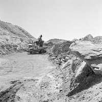 Equipment Operator Constructionman Kyle Holtzman directs Equipment Operator  Constructionman Eric Hofmans as he operates a wheel loader to move a stack  of lumber at the Ecole 5 Primary School.