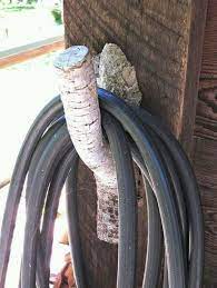 Can a garden hose wheel be mounted on a wall? Use An Old Branch To Hang Your Hose Hose Holder Garden Garden Inspiration